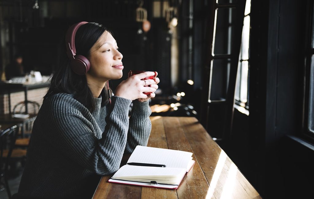 a girl relaxing with a cup on hand while listening to music